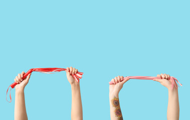 Female hands with whips from sex shop on color background