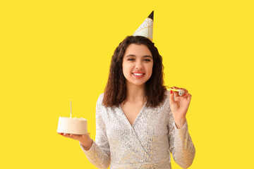 Beautiful young woman with party whistle and sweet cake celebrating Birthday on yellow background