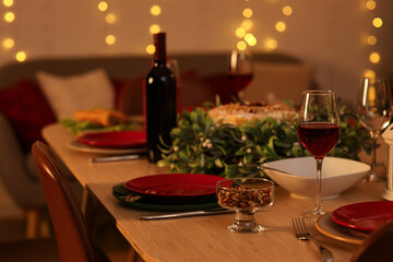 Christmas table setting with mistletoe wreath in room at night, closeup