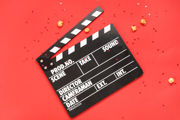 Fototapeta na wymiar Movie clapper with popcorn and confetti on red background. Valentine's Day celebration