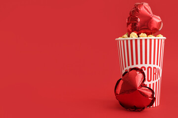 Bucket of popcorn and heart shaped air balloons on red background. Valentine's Day celebration