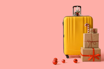 Suitcase with presents and Christmas balls on pink background
