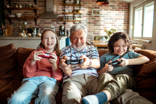 Children playing controller video games with grandpa at home