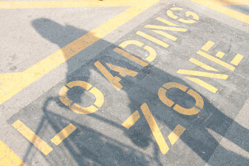 loading zone writing caption text word in yellow on black on pavement cement concrete outside with...
