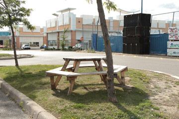 hexagon wood wooden light color picnic table on grass island in parking lot with small building...