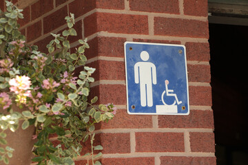 male bathroom washroom mens room square blue white symbol sign and handicap on brick wall outside...