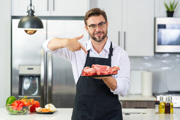 Millennial hispanic man in chef uniform hold meat beef at kitchen. Cooking meat. Restaurant menu...