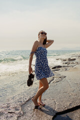 A moment of seaside solace, as a woman in a blue floral dress pauses to soak in the ocean's expanse