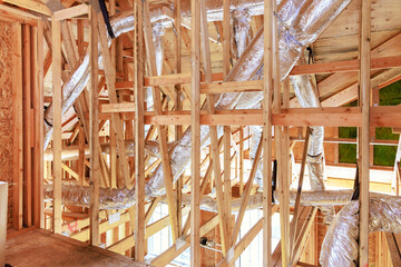 Wooden framing of new construction home with beams is attached to framework