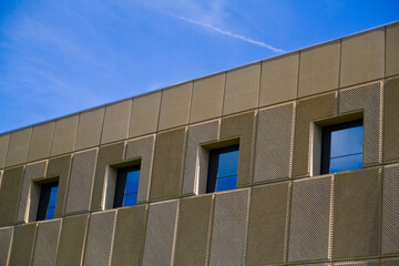 Modern Metallic Facade with Geometric Windows Under Blue Sky