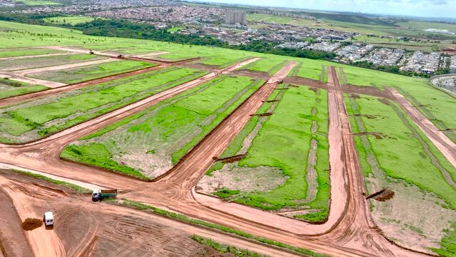 magem a&eacute;rea de canteiro de obras com tratores e caminh&otilde;es construindo loteamentos para um novo bairro na cidade de Paul&iacute;nia, S&atilde;o Paulo.