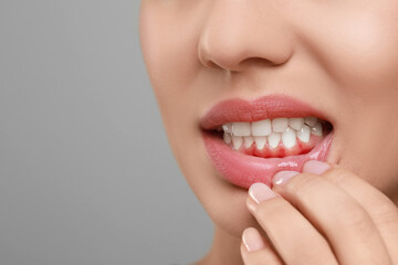 Woman showing inflamed gum on grey background, closeup. Space for text