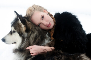 Naklejka na ściany i meble Young woman with wolf dog in snow