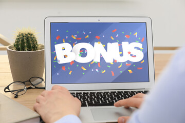 Bonus gaining. Man using laptop at table, closeup. Illustration of falling confetti and word on...
