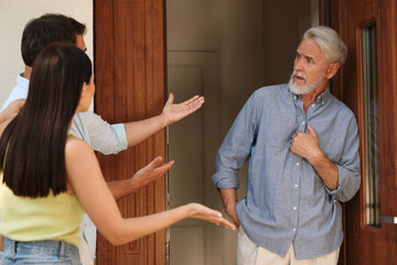 Neighbour`s quarrel. Young couple arguing with emotional senior man