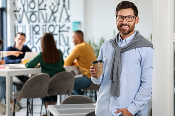 Team of employees working together in office. Happy man with paper cup of drink indoors, space for text