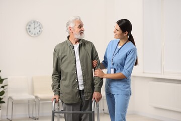 Smiling nurse supporting elderly patient in hospital