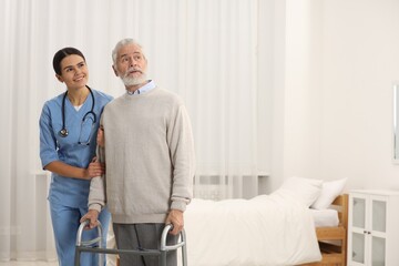 Smiling nurse supporting elderly patient in hospital. Space for text