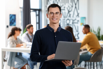 Team of employees working together in office. Happy man with laptop indoors