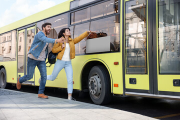Being late. Worried couple running towards bus outdoors, space for text