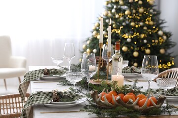 Christmas table setting with festive decor and dishware in room