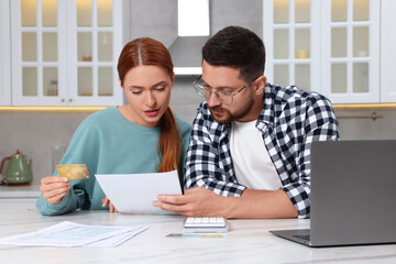 Couple with credit card using laptop for paying taxes online at home