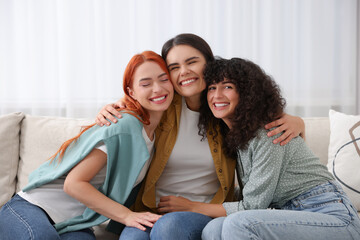 Portrait of happy young friends hugging at home