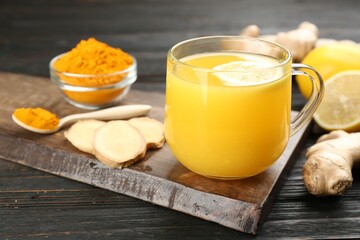 Immunity boosting drink with ginger, lemon and turmeric on dark wooden table