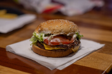 hamburguesa con queso, tomate y lechuga, sobre una servilleta blanca en un restaurante de comida rápida