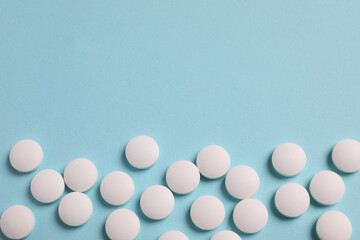 Many white pills on light blue background, flat lay. Space for text