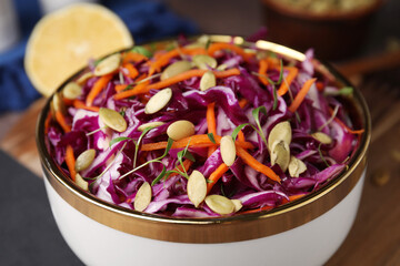 Tasty salad with red cabbage and pumpkin seeds in bowl on table, closeup