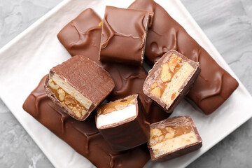 Tasty chocolate bars with nougat, caramel and nuts on table, top view