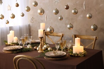 Christmas table setting with burning candles and festive decor