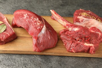 Pieces of raw beef meat and spices on grey textured table