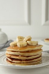 Delicious pancakes with bananas and honey on white wooden table. Space for text