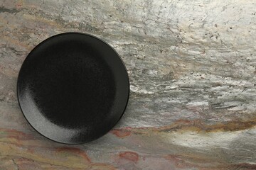 Beautiful black ceramic plate on gray textured table, top view. Space for text