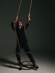 young light-skinned girl with dark bob hair in dark clothes with a rope artistic light