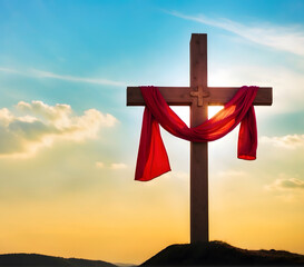 Christian cross with shroud on hill at sunset.