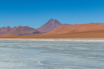 Fototapeta premium Landscape with frozen lagoon and volcano in the background, in the Atacama Desert