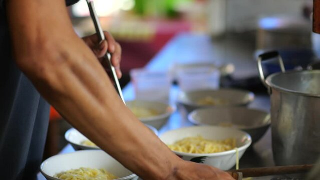 Preparing chicken noodles. View of a penjual mie ayam bakso or meatball chicken noodle seller who is making chicken noodles for the buyer. Selective focus
