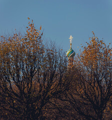 Onion dome with golden cross and autumn tree branches. Top of the Orthodox Church - Savior on the Spilled Blood, St. Petersburg, Russia.