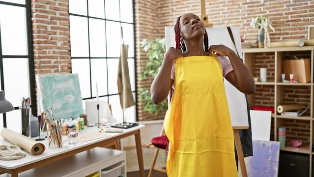Relaxed african american woman artist, beautiful in braids and apron, immersed in her craft at a canvas in art studio