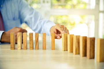 Hand to stop wooden block prevent not falling domino concepts of financial risk management and strategic planning and business challenge plan or safety insurance. - obrazy, fototapety, plakaty