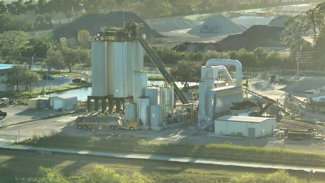 Concrete mixing factory at industrial area with cement trucks and heavy building equipment.