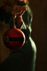A woman in a green dress holding a Christmas ornament in the dark in front of her