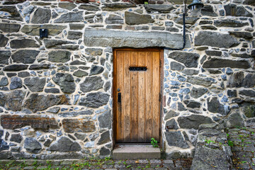 Fototapeta na wymiar Historic Akershus Castle in the city center of Oslo, Norway, architectural detail of rustic heavy wooden door in an ancient stone wall 