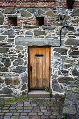 Historic Akershus Castle in the city center of Oslo, Norway, architectural detail of rustic heavy wooden door in an ancient stone wall 
