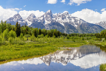 The snow-capped peaks of the Cathedral Group of the Teton Mountain Range rise above the Snake River Valley at Schwabacher's Landing, Grand Teton National Park, Wyoming. - 690466595