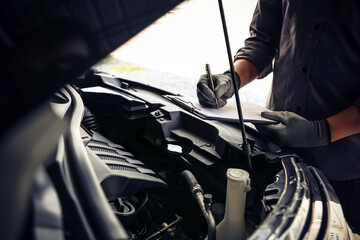 Hand auto mechanic using checklist after service repairing car engine problem concepts of check and...