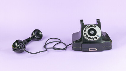 Black vintage handset with the handset off on a purple background.